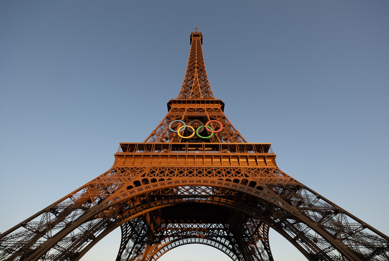 Eiffel Tower adorned with Olympic rings at sunset in Paris, France, offering a stunning view of this iconic landmark.
